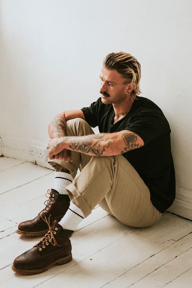 Alternative man sitting on a white wooden floor