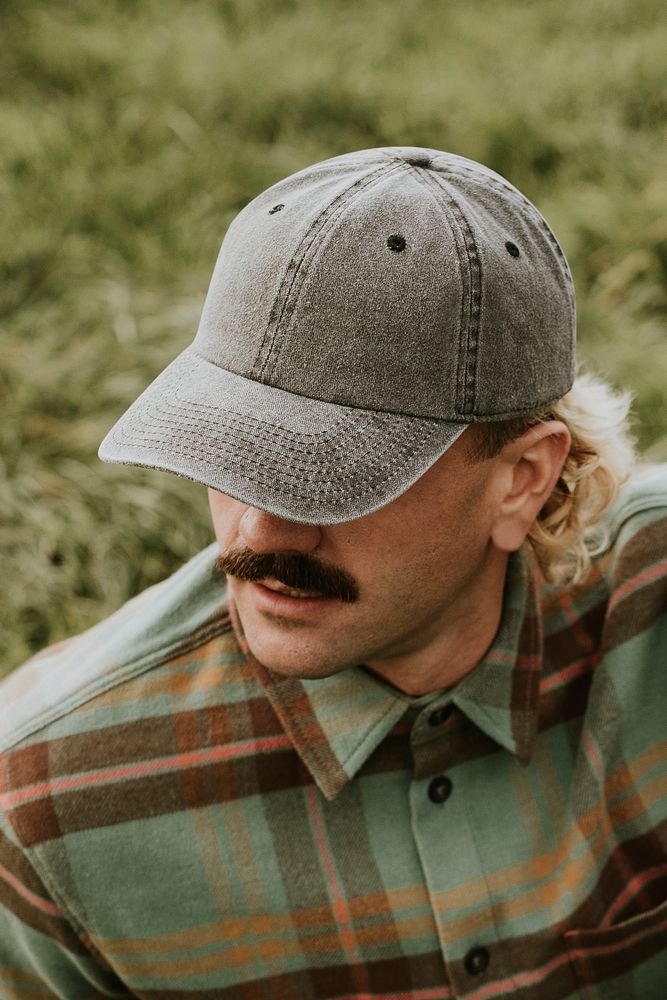 Man with mustache wearing a cap and green flannel shirt