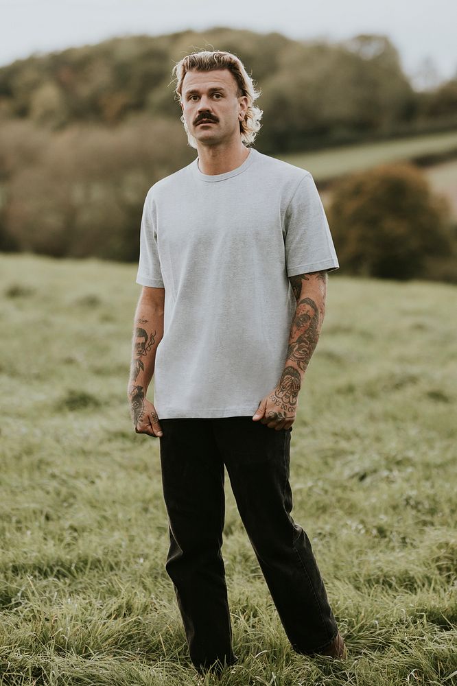 Attractive man in gray t-shirt with design space standing in countryside