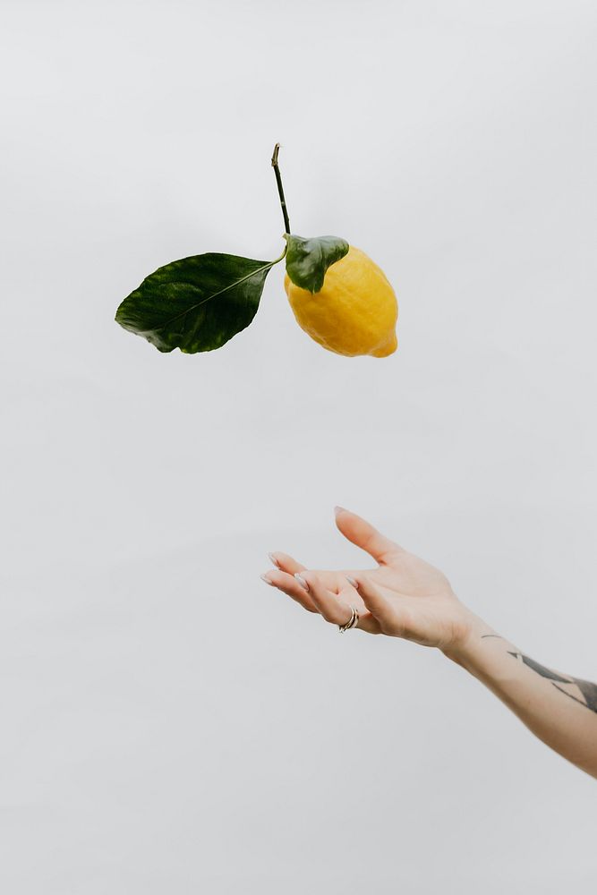 Tattooed hand throwing a lemon up in the air