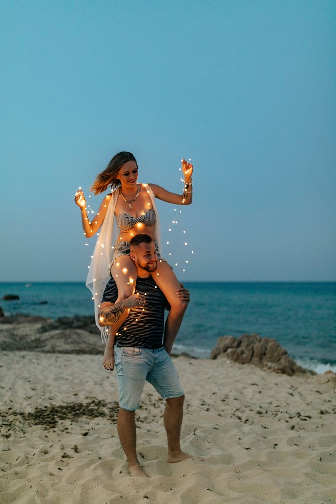 Woman riding on man's shoulder at the beach