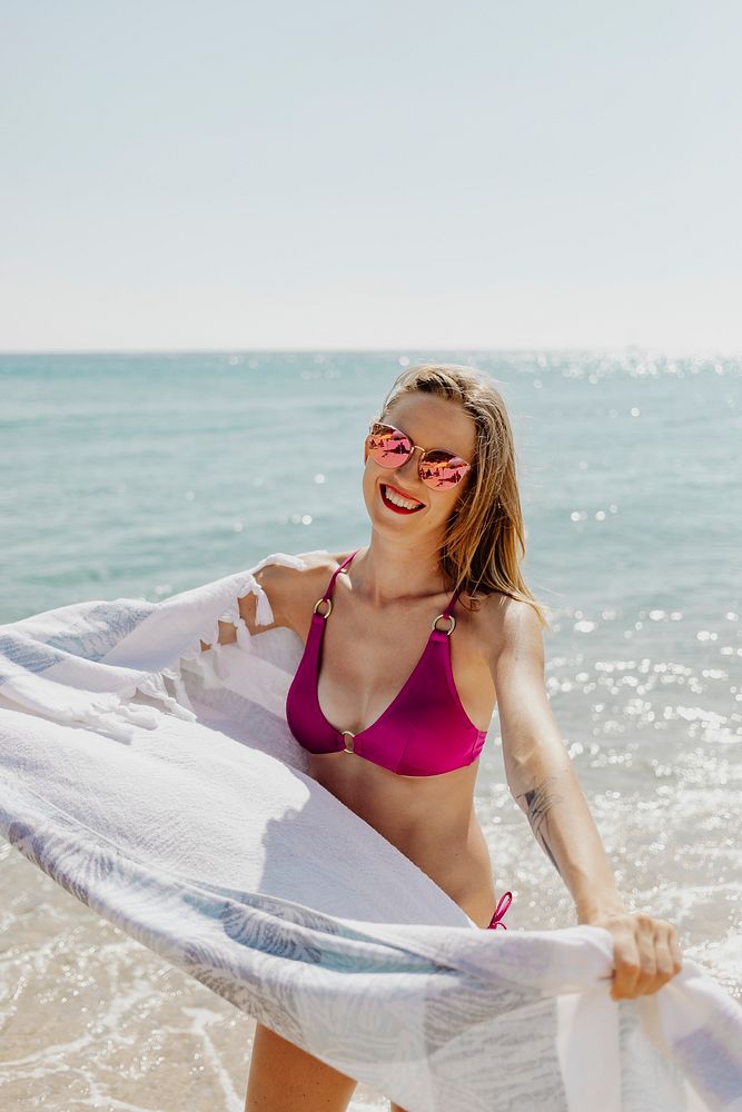 Girl in a pink bikini with a towel at the beach