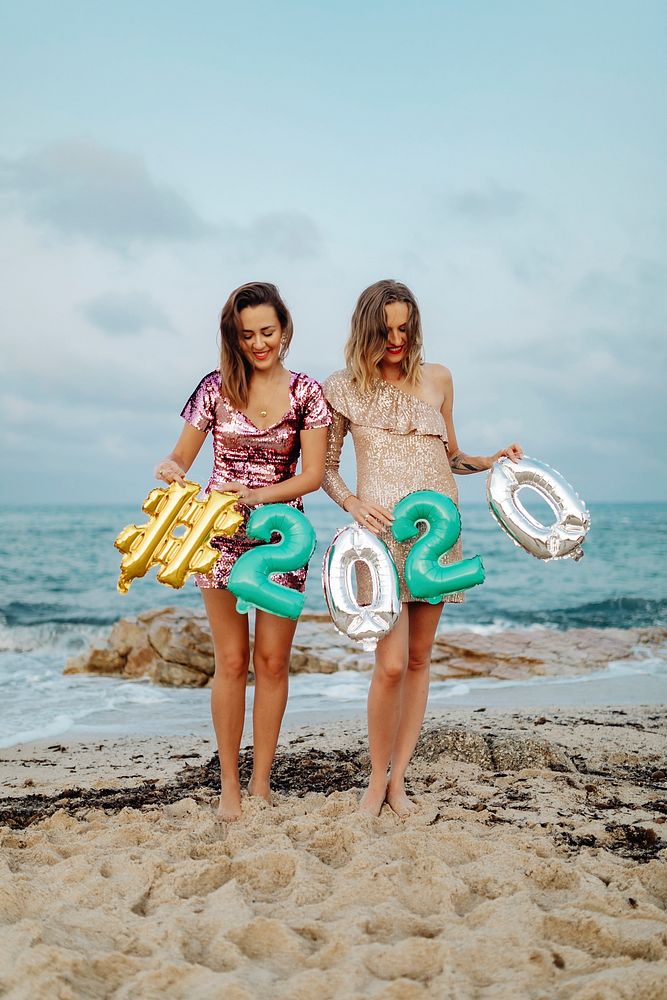 Girls carrying a 2020 foil balloon at the beach party