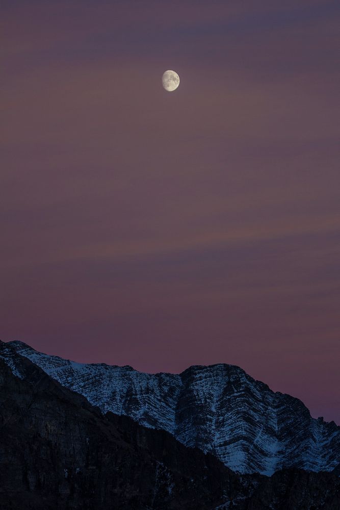 Half moon rising over mountain range. Original public domain image from Flickr