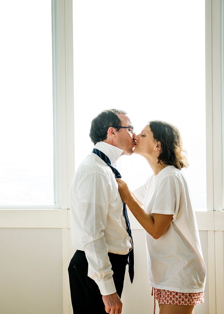 Woman kissing husband while dressing up