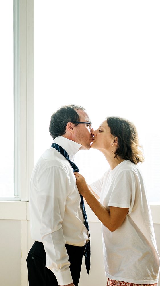 Woman kissing husband while dressing up mobile phone wallpaper