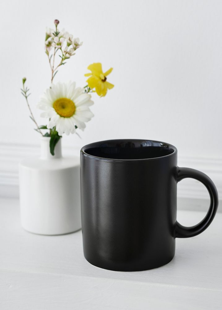 Black coffee cup daisies in a vase