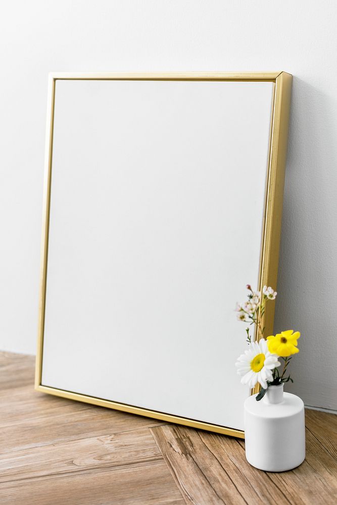 Blank golden frame by a vase of flowers