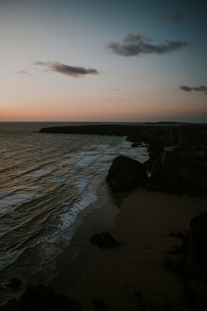 Orange sky over the gloomy rocky beach