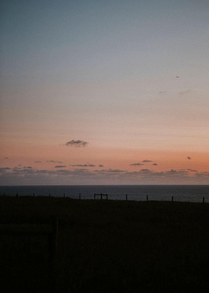 Orange sky over the gloomy fenced beach