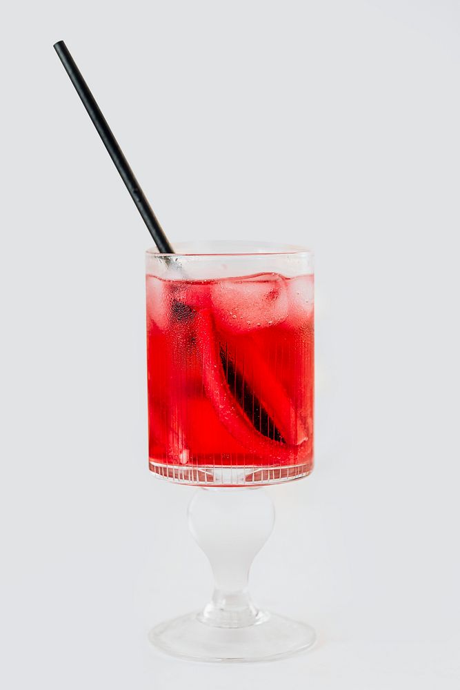 Red drink in a glass with a straw on a white table