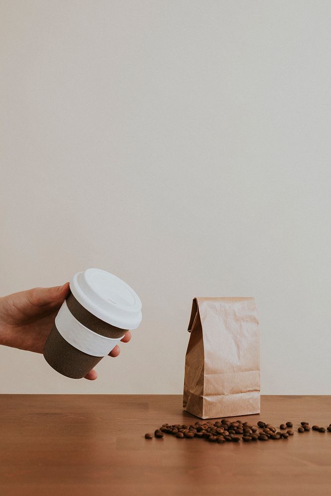 Hand holding a cork reusable cup with coffee beans