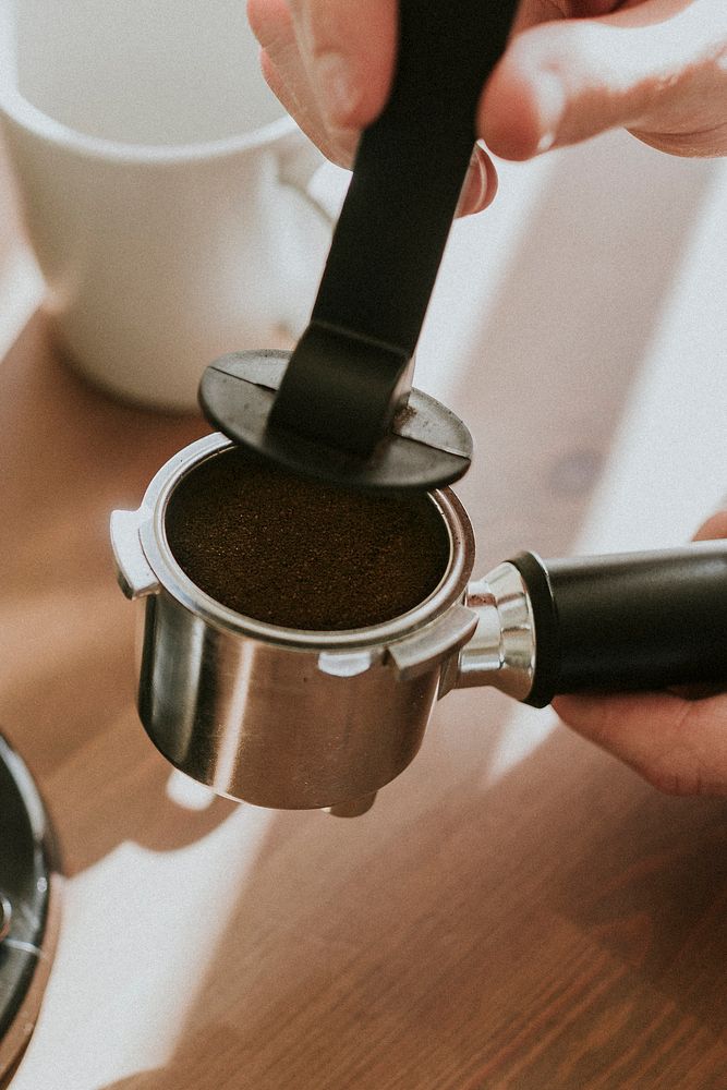 Barista pressing ground coffee in a coffee machine filter