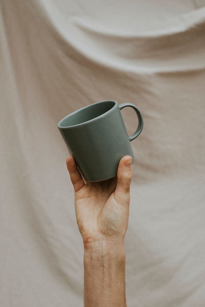 Hand holding a gray ceramic coffee cup