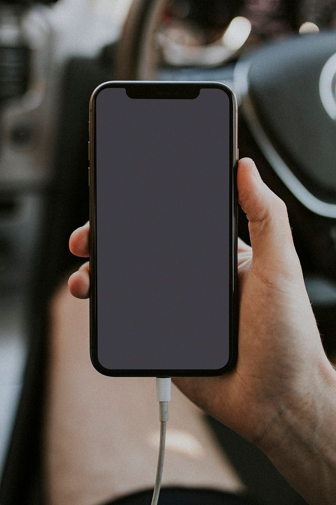 Hand holding a blank screen smartphone in a car