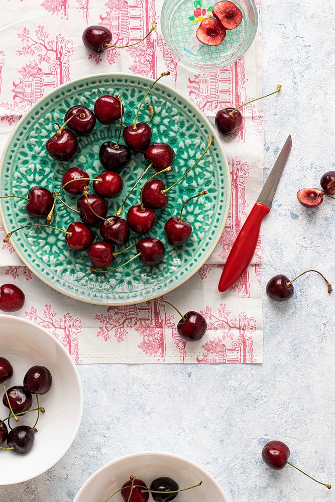 Fresh ripped red cherries on a green plate flatlay