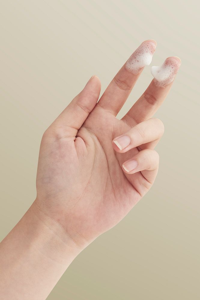 Hand with white facial foam cleanser