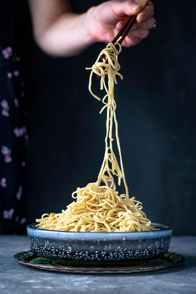 Woman eating Asian egg noodles with chopsticks food photography