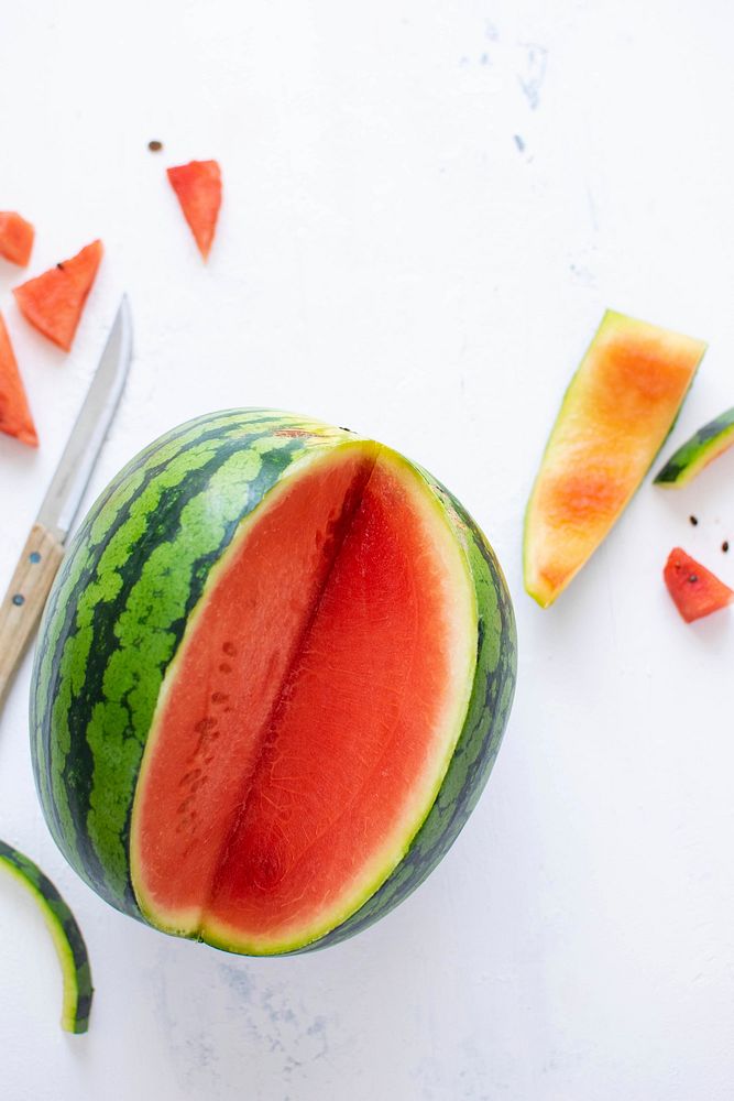 Watermelon with knife on white table flat lay