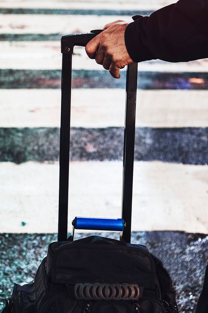 Man with a bag waiting to cross the wet road