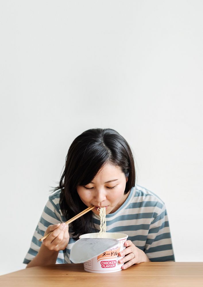 Asian woman eating instant noodles during coronavirus quarantine