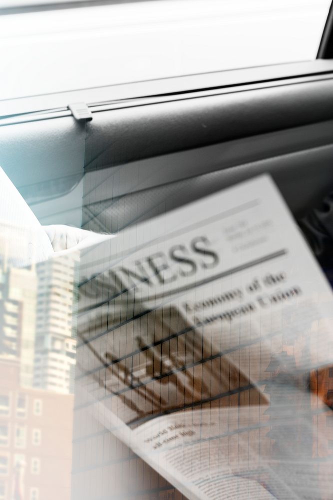 Businessman reading newspaper in car with city background overlay