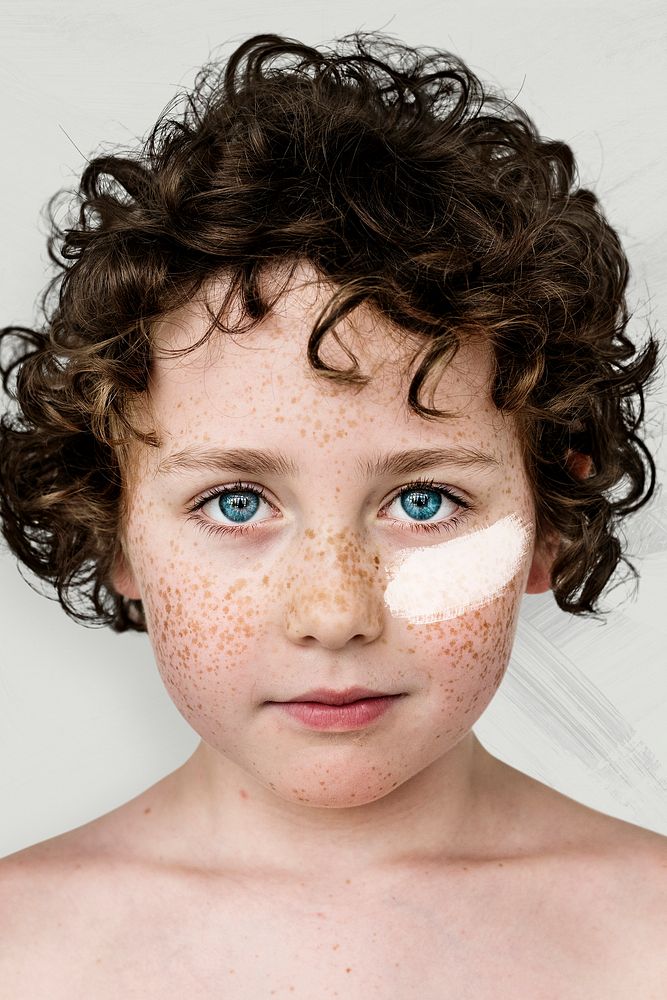 Curly haired boy with freckles and white paint on his cheek