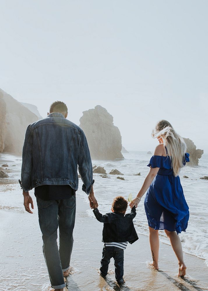 Interracial family walking along the beach in California text space