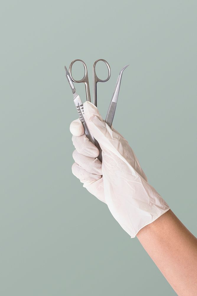 Gloved hand holding stainless steel medical instruments