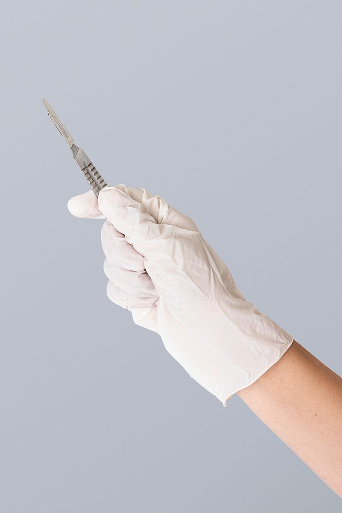 Doctor's hand in a white glove holding a scalpel