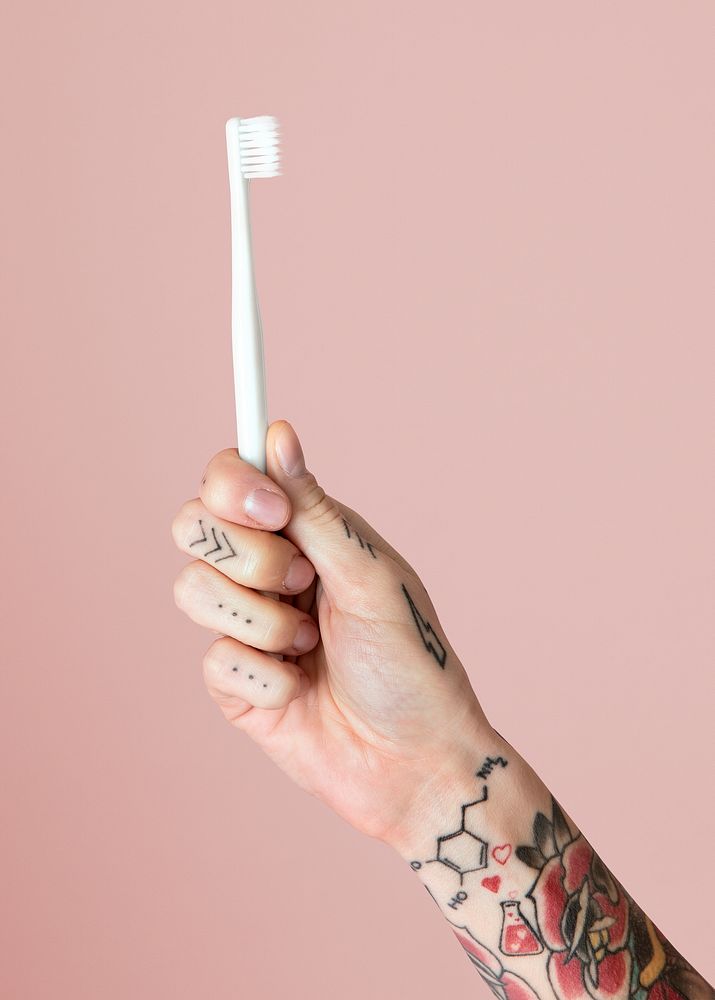 Tattooed hand holding a toothbrush