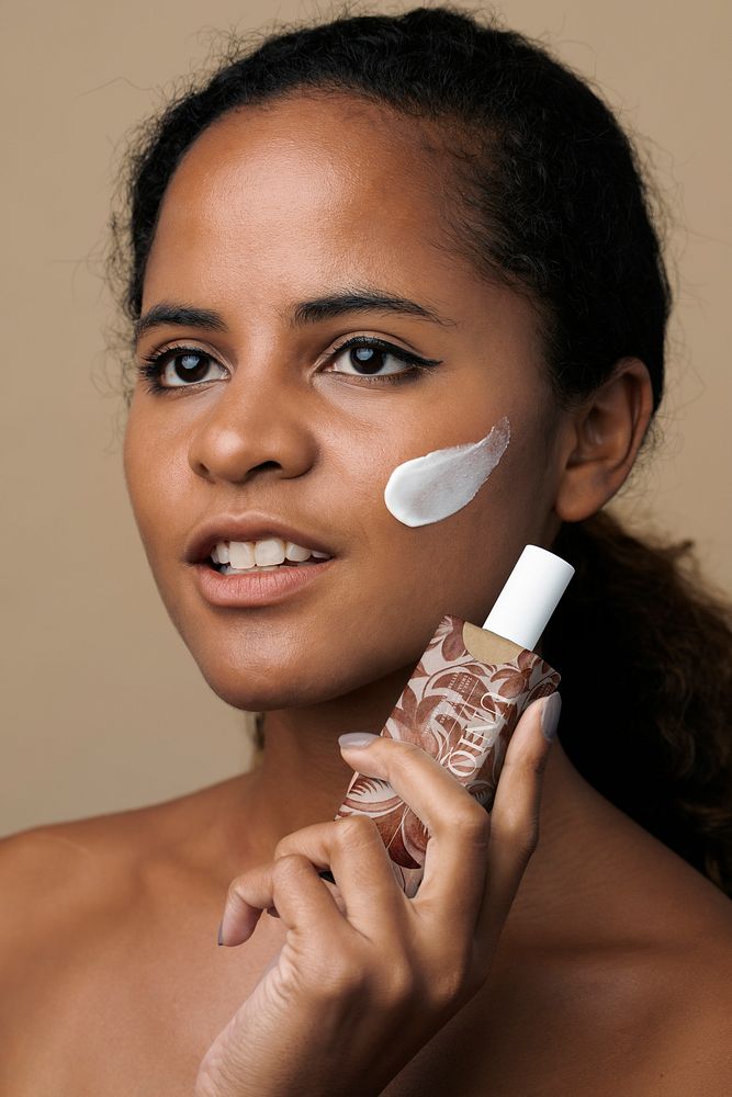 Black woman holding facial cream bottle