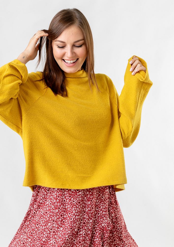 Cheerful woman wearing a mustard yellow sweater on a red flower dress