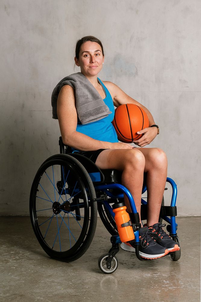 Happy female athlete in a wheelchair with a basketball
