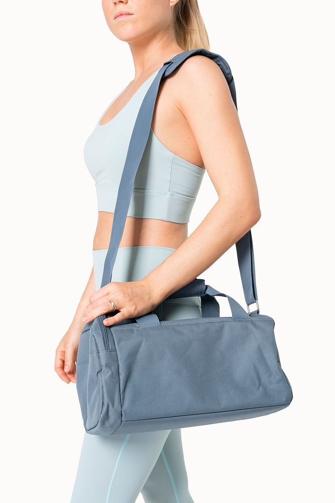 Sporty woman carrying blue duffle bag gym essentials studio shoot