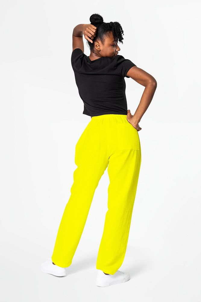 Woman in neon yellow sweatpants and black tee street apparel rear view