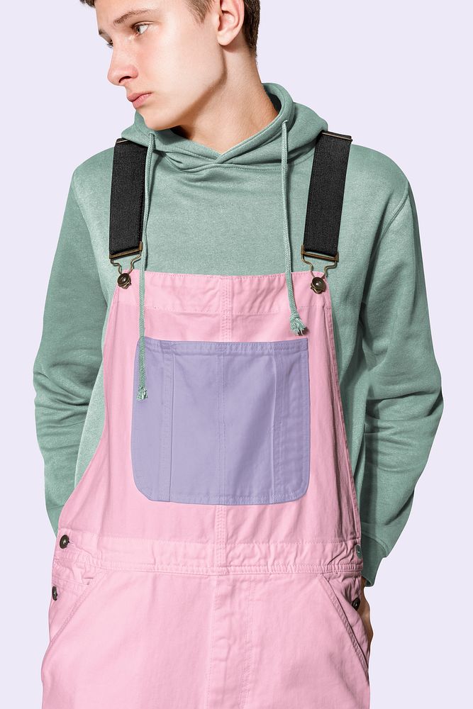 Teenage boy in pink dungarees and green hoodie streetwear photoshoot