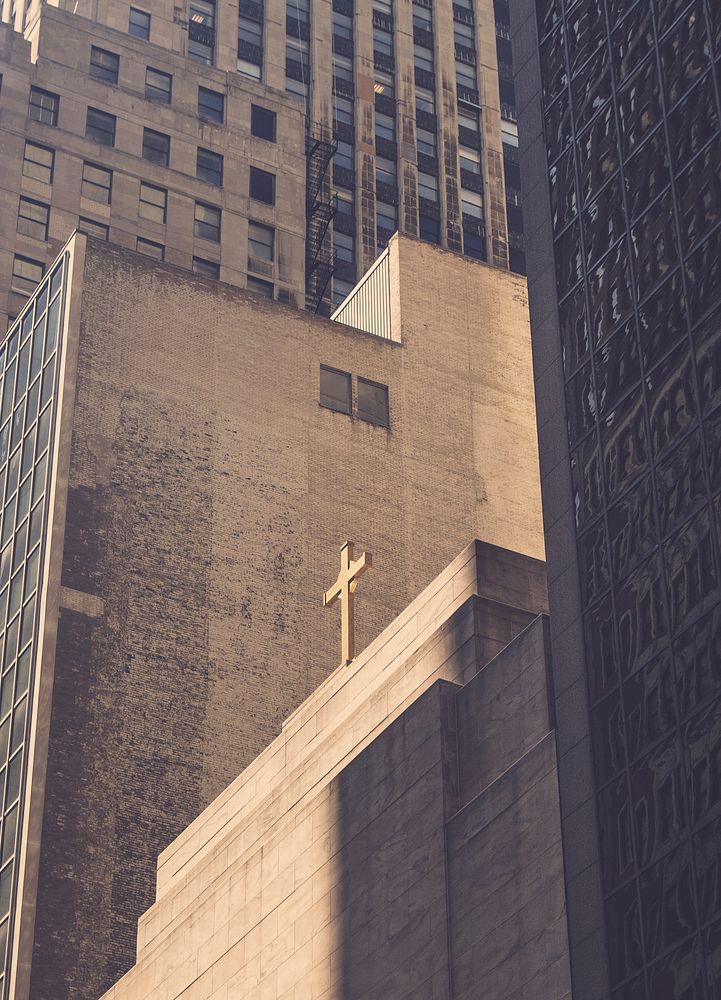 Cross on a simple concrete church building surrounded by high rise buildings. Original public domain image from Wikimedia…