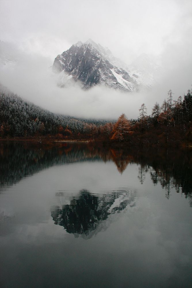 Mountain peak reflects in calm waters surrounded by autumnal trees. Original public domain image from Wikimedia Commons