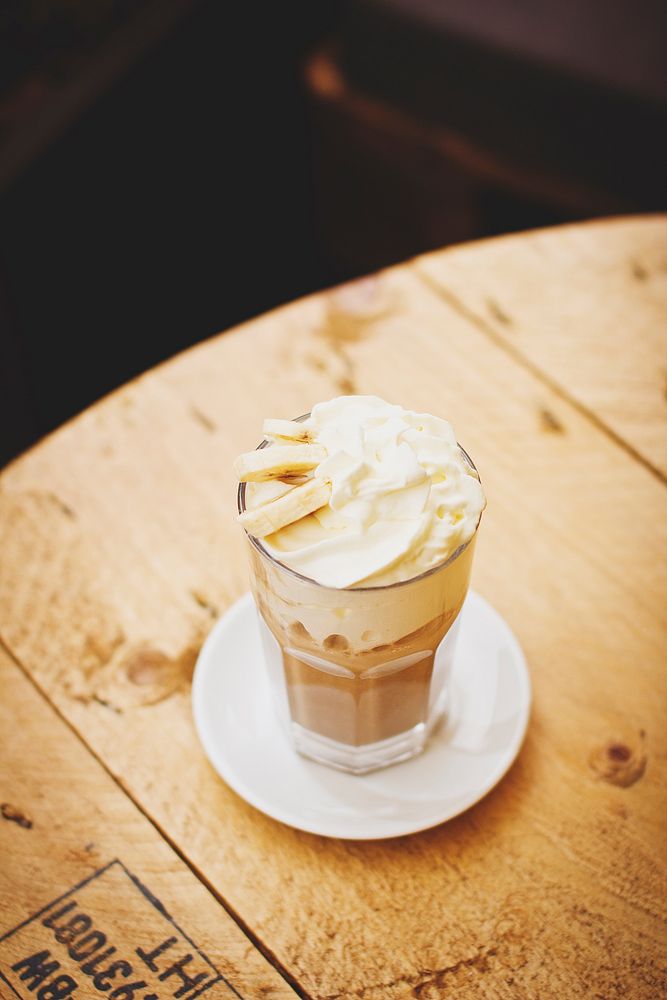 Coffee drink with whipped cream and banana sits on a cafe table. Original public domain image from Wikimedia Commons