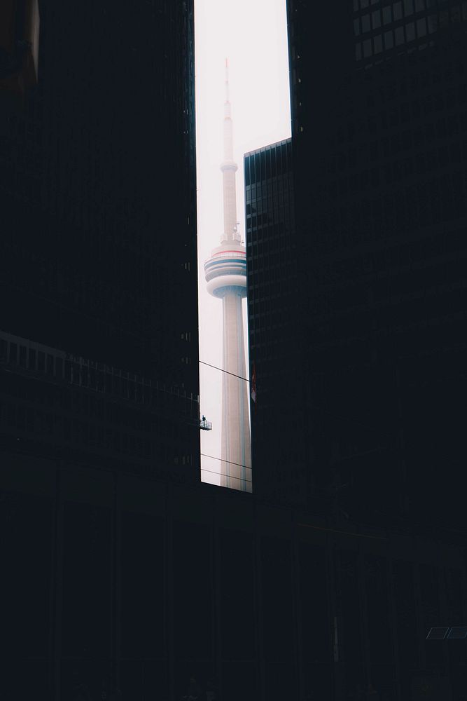 The CN Tower in Toronto framed by black high-rises. Original public domain image from Wikimedia Commons