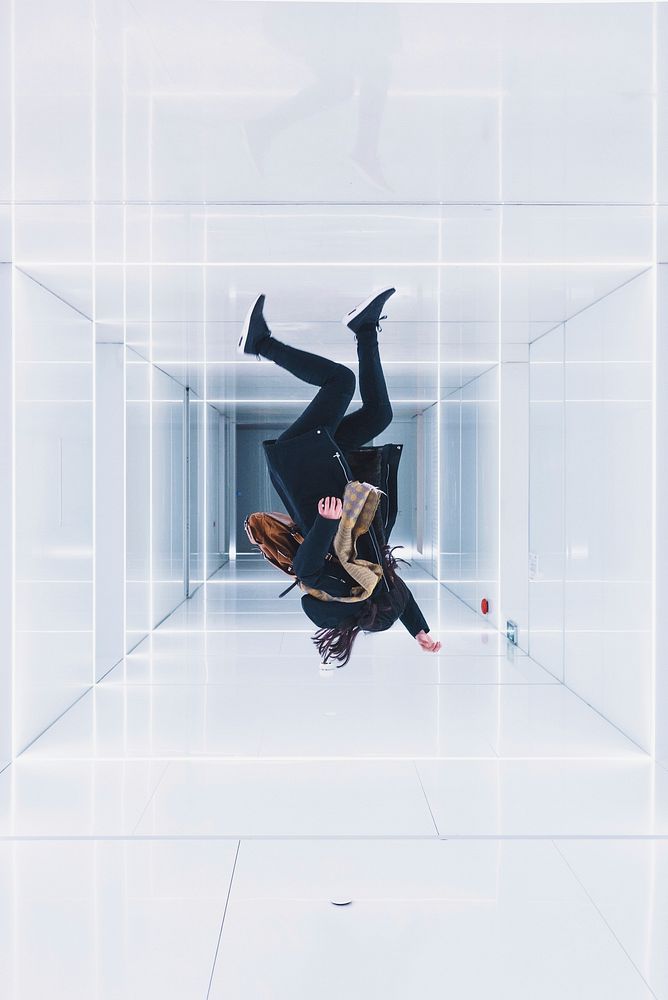 Optical illusion of a person jumping upside down in a white walled room. Original public domain image from Wikimedia Commons
