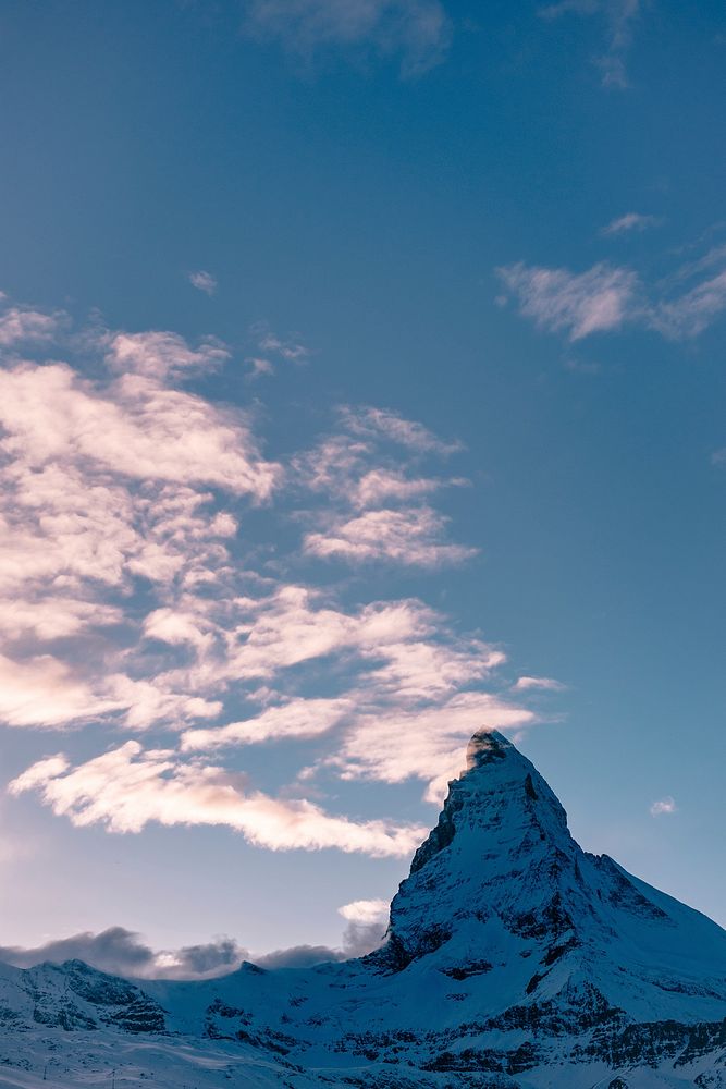 The Matterhorn's snowy peak reaches up to touch clouds in the sky. Original public domain image from Wikimedia Commons