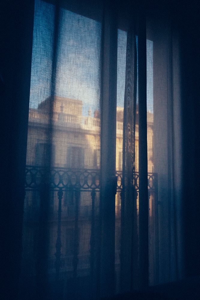 The view outside a window through a blue curtain.. Original public domain image from Wikimedia Commons