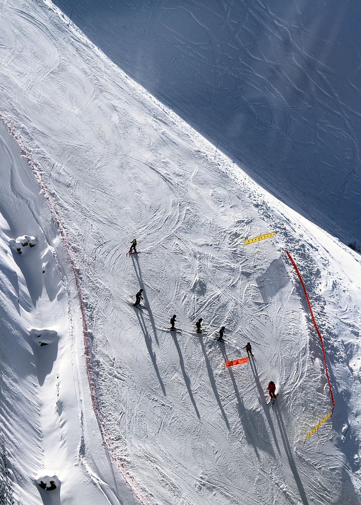 A drone shot directly above seven skiers preparing for a slope race. Original public domain image from Wikimedia Commons