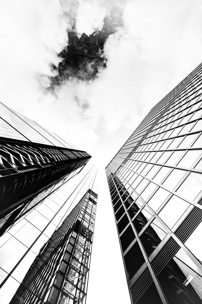 A low-angle monochrome shot of glass skyscraper facades under cloudy sky. Original public domain image from Wikimedia Commons