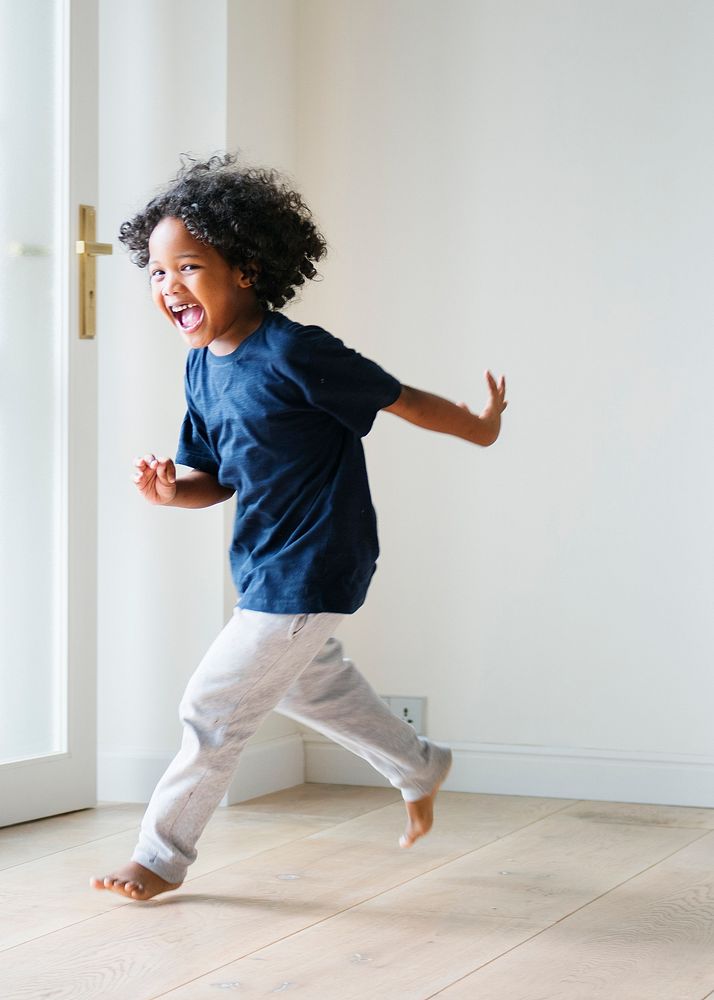 Two black kids playing and chasing each other in an empty room