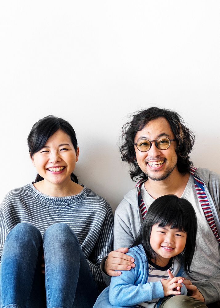 Smiling Japanese family with a daughter sitting on the floor text space