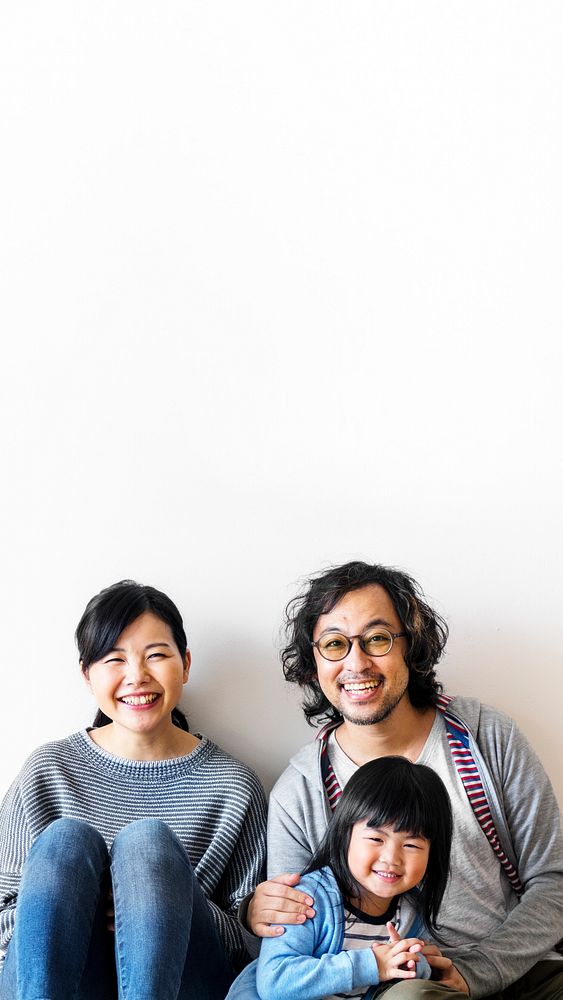 Smiling Japanese family with a daughter sitting on the floor black space 