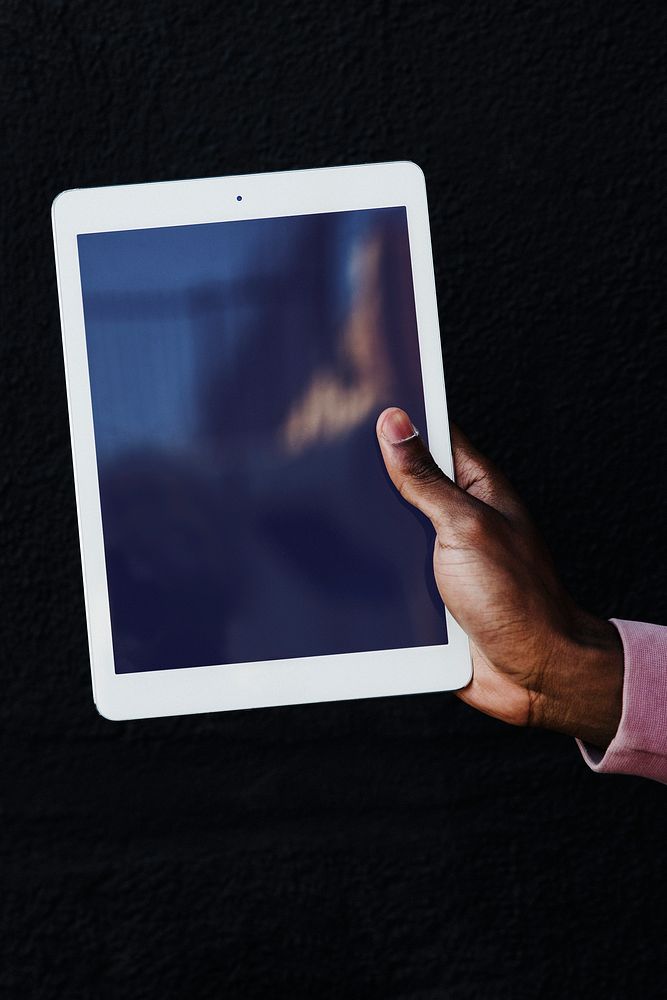 Hand holding a digital tablet on black background